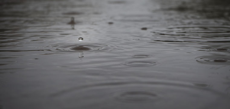 A close-up of a raindrop landing in a puddle